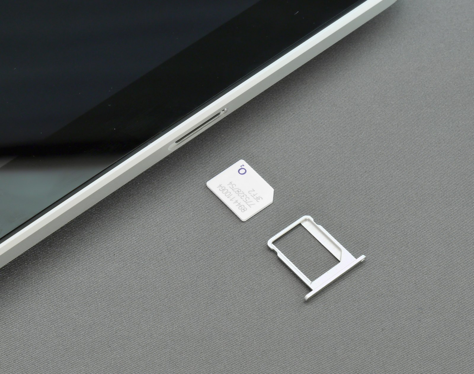 A SIM card beside its tray and a phone